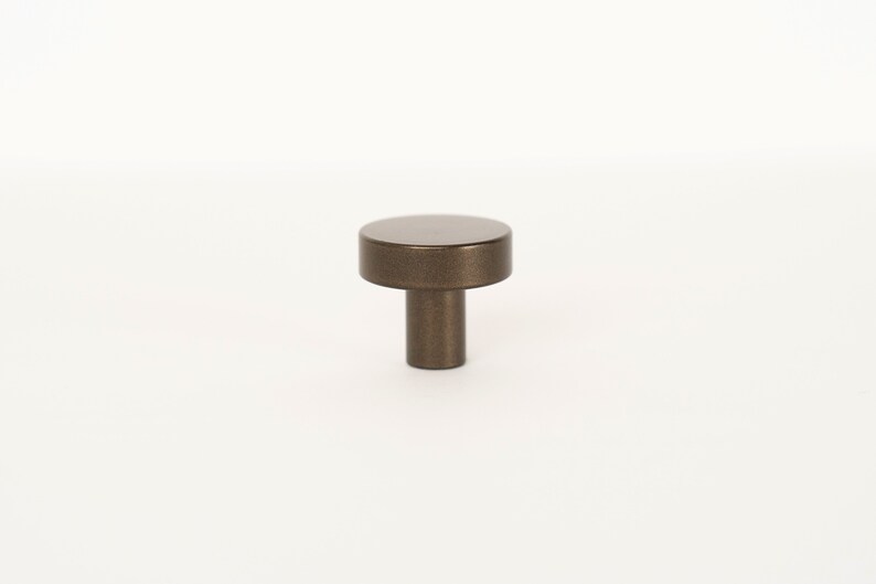 Op de afbeelding: Een ronde, bronzen kastknop met een licht getextureerd oppervlak.