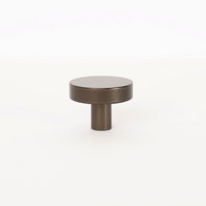 Op de afbeelding: Een ronde, bronzen kastknop met een korte, cilindrische steel.