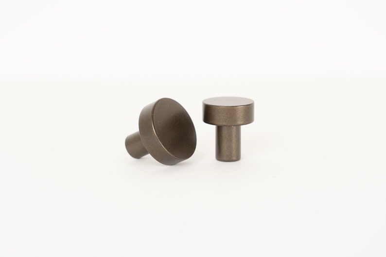 Op de afbeelding: Twee ronde, bronzen kastknoppen met een cilindrische basis.