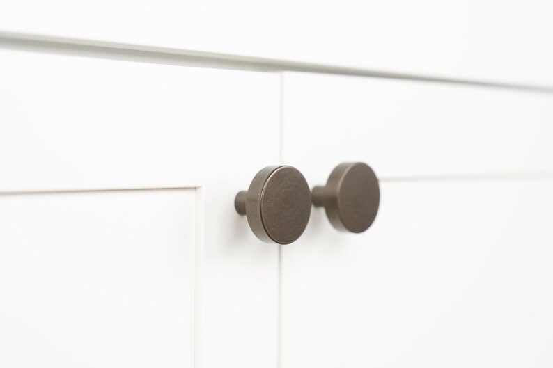 Op de afbeelding: Twee ronde, geborstelde nikkel kastknoppen met een licht getextureerde afwerking.