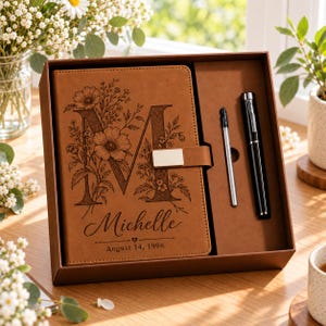 Può includere: Un diario in similpelle color cuoio con una lettera M floreale, il nome Michelle e la data 14 agosto 1996 incisi sulla copertina. Il diario presenta una chiusura magnetica argentata ed è presentato in una scatola con una penna nera e ricarica.