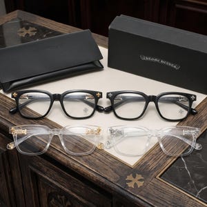 Puede incluir: Dos pares de gafas con montura negra y dos pares de gafas con montura transparente, con detalles de cruces metálicas en las patillas. Las gafas vienen con un estuche de cuero negro y una caja negra con el texto Chrome Hearts impreso en el frente.