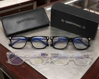 Puede incluir: Dos pares de gafas con montura negra y dos pares con montura transparente, con detalles metálicos de cruces en las patillas. Cada par incluye un pequeño logotipo circular en el cristal. Un estuche de cuero negro y una caja negra muestran el logotipo de Chrome Hearts.
