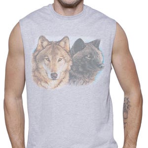 May include: A sleeveless gray shirt featuring a detailed illustration of two wolves. One wolf is brown and tan, the other is black. The shirt is worn by a person wearing dark blue jeans.
