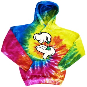 May include: Tie-dye hoodie featuring a cartoon image of two hands holding a green marijuana leaf. The hoodie is a blend of blue, green, yellow, orange, pink, and red.