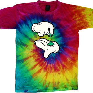 May include: A tie-dye t-shirt featuring a cartoon hand design. The hand is holding a green leaf. The shirt is a mix of pink, blue, green, yellow, and orange.