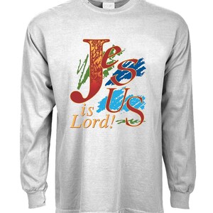 May include: A gray long-sleeve t-shirt with a colorful graphic design that reads "Jesus is Lord!" The graphic features a stylized "J" and "US" with a red, orange, yellow, blue, and green color scheme.