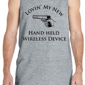 Könnte beinhalten: Graues Tanktop mit dem Text "Lovin' My New Hand Held Wireless Device" und einer Handfeuerwaffen-Grafik. Text und Grafik sind schwarz. Das Tanktop wird von einer Person getragen.
