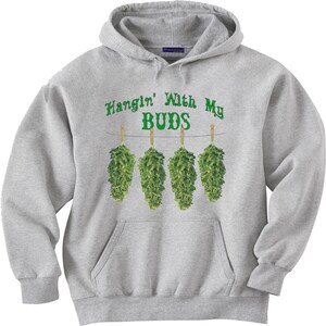 May include: A light gray hoodie with a front pocket and drawstring hood. The front features the text "Hangin' With My BUDS" in green above four green buds hanging from a string.