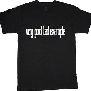 以下が含まれることがあります： 「very good bad example」という白い文字が書かれた黒いTシャツ。