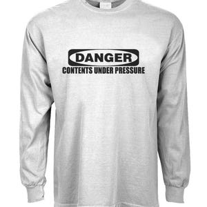 May include: A gray long-sleeve t-shirt with a black warning sign that reads "DANGER CONTENTS UNDER PRESSURE".