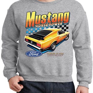 May include: A gray sweatshirt featuring a vintage Mustang car graphic. The design includes the word "Mustang" in a bold, orange and yellow font, along with "Horse Power" and the Ford logo. The car is yellow with black accents.