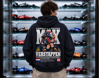 Könnte beinhalten: Ein dunkelblauer Kapuzenpullover mit einer großen Grafik auf der Rückseite, die den Formel-1-Fahrer Max Verstappen mit Rennhelm zeigt. Der Text lautet Formula 1 Driver Max Verstappen, ergänzt durch eine niederländische Flagge und die Zahl 01.
