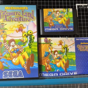 Può includere: Un set di videogiochi Sega Mega Drive intitolato McDonald's Treasure Land Adventure, che include una custodia, una cartuccia di gioco nera e un manuale di istruzioni. La copertina mostra Ronald McDonald su una teleferica con personaggi.