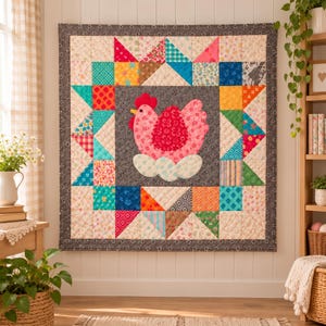 May include: A square quilted wall hanging featuring a central dark grey panel with an appliqué of a pink hen sitting on white eggs. The border consists of a colourful patchwork of various geometric and floral fabric squares in bright shades.
