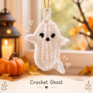 Könnte beinhalten: Ein weißes Häkel-Gespenst als Anhänger mit zwei schwarzen Augen und einem kleinen schwarzen Mund, aufgehängt an einer braunen Schnur. Das Gespenst hat eine Schlaufe zum Aufhängen. Der Text "Crochet Ghost" steht unten im Bild.