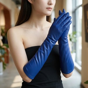 May include: A pair of long, elbow-length gloves in a vibrant royal blue color. The gloves feature a smooth, matte finish and extend past the elbow, covering the forearms with a fitted, streamlined silhouette that reaches toward the upper arm.