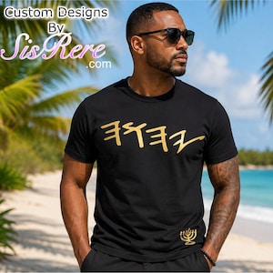 May include: A black short-sleeved t-shirt featuring gold-colored Paleo-Hebrew lettering across the chest and a small gold menorah graphic near the bottom hem. The shirt has a crew neckline and is made of a solid black fabric.