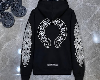 Può includere: Una felpa nera con cappuccio caratterizzata da una grande grafica circolare bianca sul retro con il testo Chrome Hearts. Le maniche sono decorate con motivi a croce floreale bianchi e un piccolo logo Chrome Hearts è stampato sull'orlo.