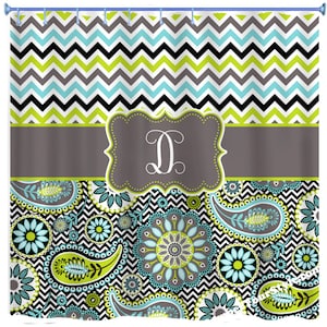 May include: A shower curtain with a black, white, green, and blue paisley and chevron pattern. The curtain has a gray band with a white letter "D" in a decorative frame.