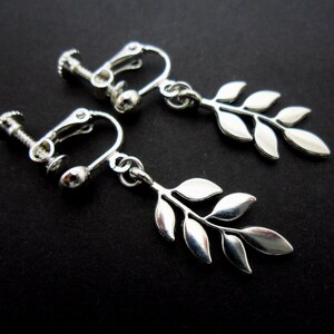 Peut inclure: Boucles d'oreilles clips argentées avec un motif de feuilles délicat. Les boucles d'oreilles sont dotées d'une fermeture à vis pour une tenue sécurisée.