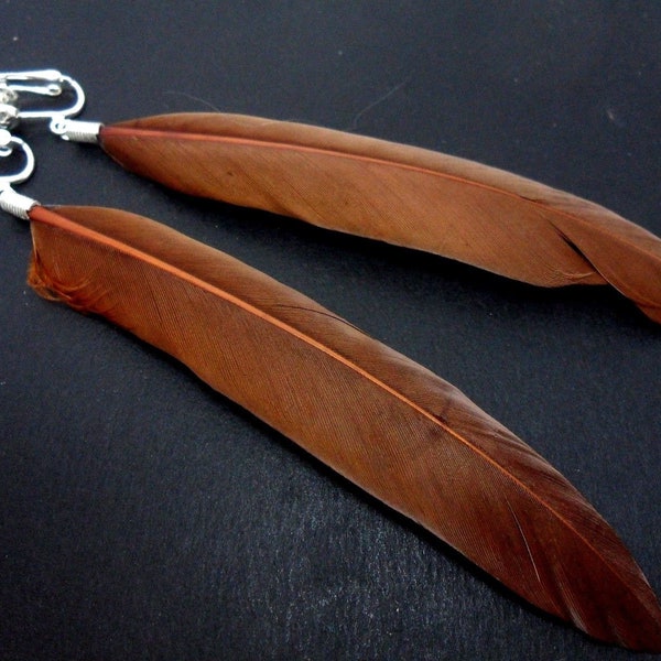 A pair of long brown feather dangly clip on earrings.