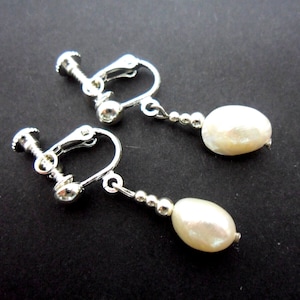 May include: A pair of silver clip-on earrings with white pearl drops.