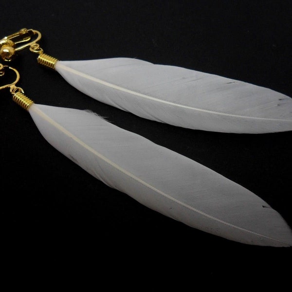 A pair of long gold colour and white feather dangly clip on earrings.