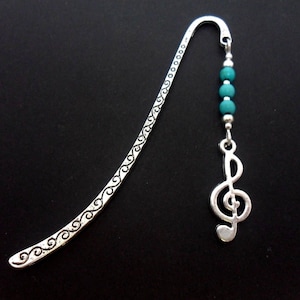 May include: Silver bookmark with a treble clef charm and turquoise beads. The bookmark has a decorative design along the edge.