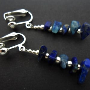 May include: A pair of silver clip-on earrings with a dangling chain of blue lapis lazuli gemstone beads.