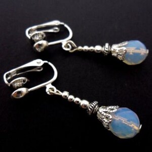 May include: A pair of silver clip-on earrings with a teardrop-shaped opal-like stone on each earring.