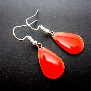 May include: A pair of silver dangle earrings with red teardrop-shaped charms.
