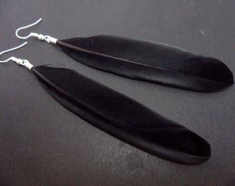 A pair of long black feather dangly earrings.