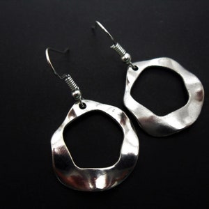 May include: A pair of silver earrings with a wavy, irregular, open circle design. The earrings have a simple hook fastening.