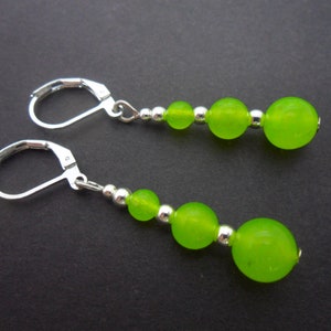 May include: A pair of silver earrings with green glass beads. Each earring has four beads, with the largest bead at the bottom.