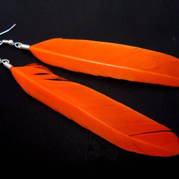 Une paire de longues orange boucles d’oreilles plumes pendantes.