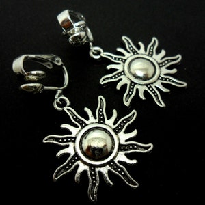 May include: A pair of silver clip-on earrings with a sun design. Each earring features a round sun with a textured surface and radiating rays.