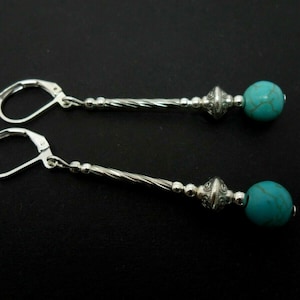 Op de afbeelding: Zilveren oorhangers met turquoise kralen en een gedraaid zilverdraadontwerp.