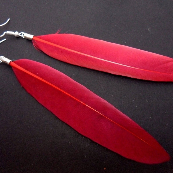 A pair of long red feather dangly earrings.