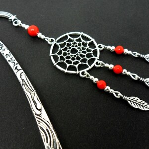 May include: Silver bookmark with a dreamcatcher charm and red beads. The bookmark has a decorative design on the handle.