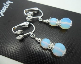 May include: A pair of silver clip-on earrings with two white opal beads on each earring.