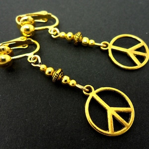 A pair of cute little gold tone  peace sign dangly clip on earrings.