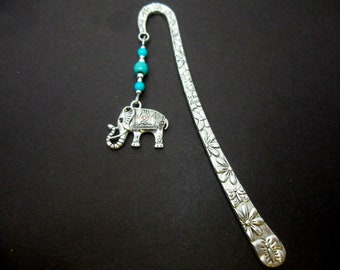May include: Silver bookmark with a detailed floral design and a silver elephant charm with turquoise beads.