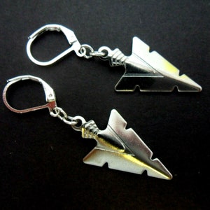 May include: A pair of silver arrowhead earrings with leverback closures. The arrowheads are detailed with a textured design.