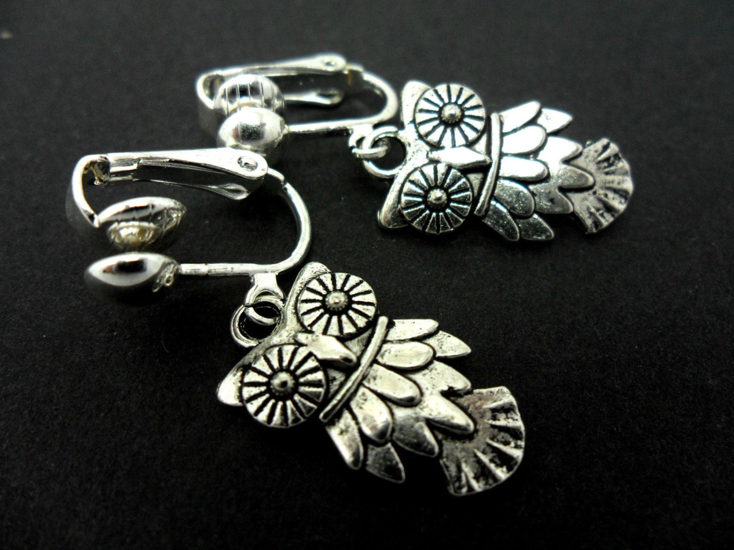 A pair of cute little tibetan silver owl themed  dangly clip on  earrings.