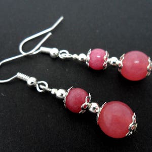 Può includere: Un paio di orecchini d'argento con perline di pietre preziose rosa. Gli orecchini hanno un design a goccia con due perline su ogni orecchino.