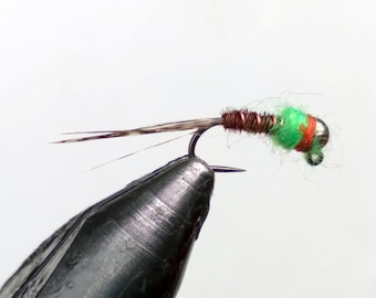 May include: A green and orange fly fishing lure with a copper wire body and a silver bead head.
