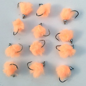 May include: Twelve peach-colored fly fishing lures with silver beads and hooks.
