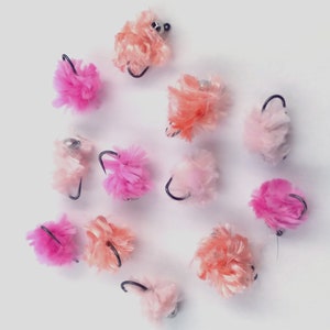 May include: A collection of 12 pink and peach fluffy pom-pom fishing lures with black hooks.