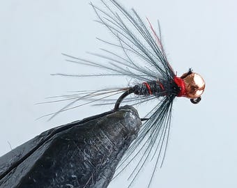 May include: A black and red fly fishing lure with a copper bead head. The lure is tied with black feathers and a red thread.